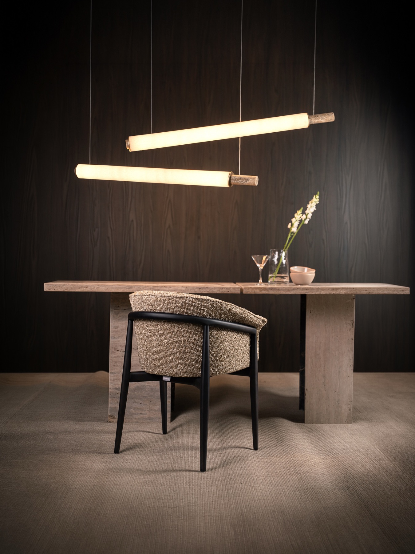 Cadeira Eileen em mesa de travertino sob luminárias lineares