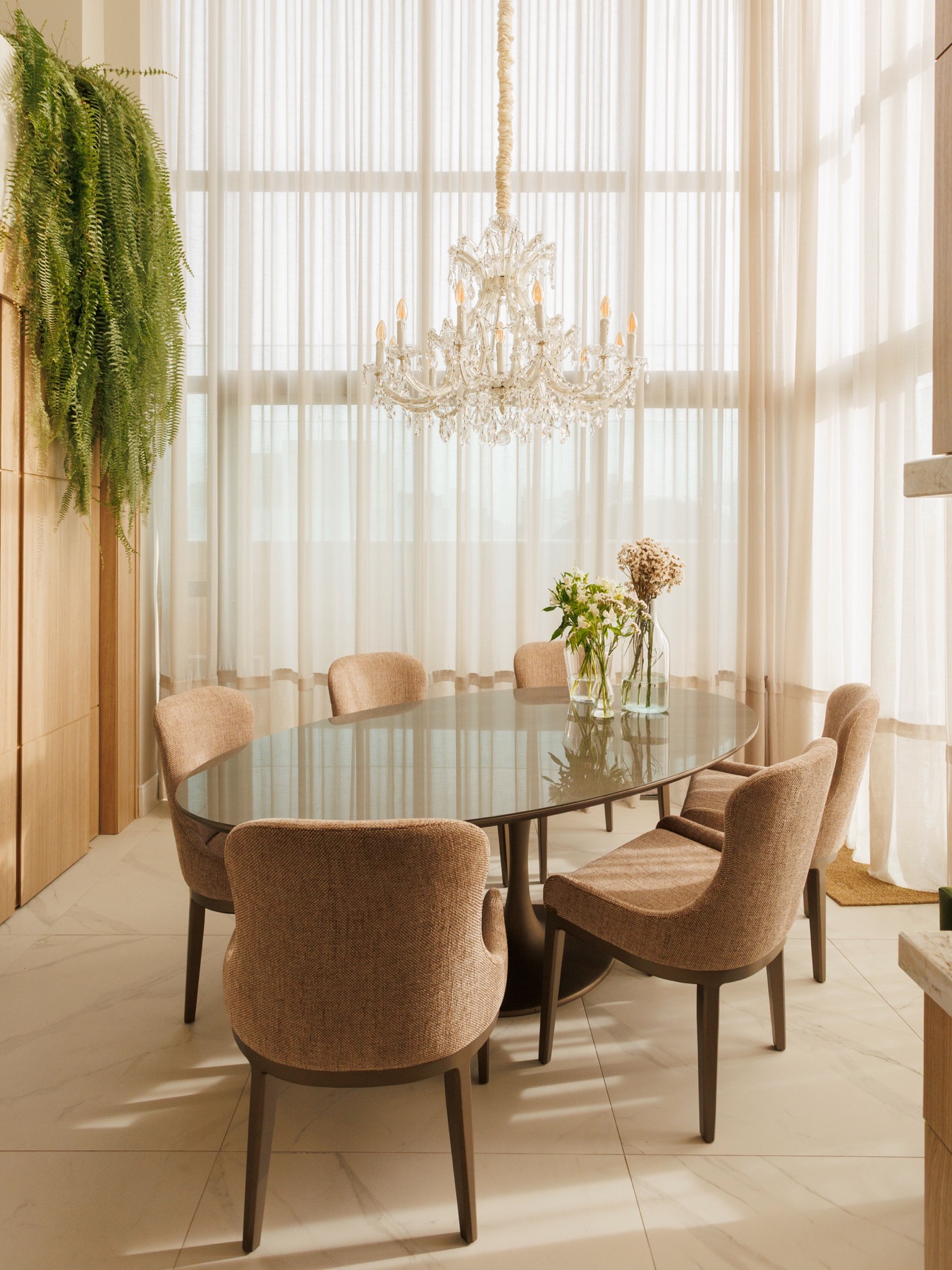 Sala de jantar com lustre de cristal e cadeiras em veludo